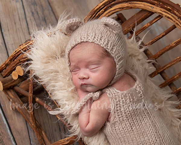 newborn baby boy with brown teddy bear hat sleeping